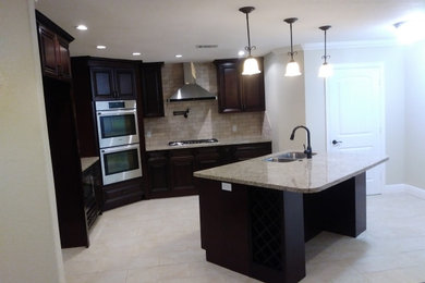 Inspiration for a ceramic tile and multicolored floor kitchen remodel in Houston with an undermount sink, recessed-panel cabinets, dark wood cabinets, granite countertops, brown backsplash, ceramic backsplash, stainless steel appliances, an island and gray countertops