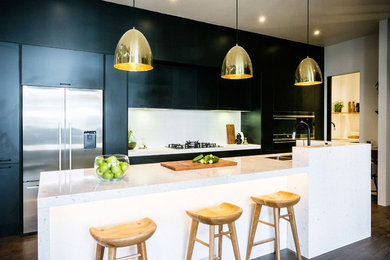 Inspiration for a contemporary u-shaped kitchen in Melbourne with a drop-in sink, flat-panel cabinets, black cabinets, stainless steel appliances, dark hardwood floors and with island.