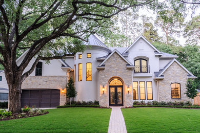 Large gray two-story stucco house exterior idea in Houston with a mixed material roof