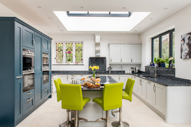 Inspiration for a mid-sized transitional u-shaped eat-in kitchen in Surrey with recessed-panel cabinets, blue cabinets, granite benchtops, panelled appliances, ceramic floors, with island, beige floor, an undermount sink and grey benchtop.