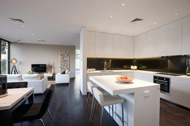 Design ideas for a mid-sized modern l-shaped kitchen in Melbourne with a drop-in sink, flat-panel cabinets, quartz benchtops, blue splashback, glass sheet splashback, stainless steel appliances, dark hardwood floors, with island and white cabinets.