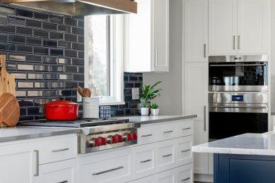 Inspiration for a mid-sized transitional l-shaped medium tone wood floor and brown floor eat-in kitchen remodel in Minneapolis with a farmhouse sink, shaker cabinets, white cabinets, quartz countertops, blue backsplash, ceramic backsplash, stainless steel appliances, an island and gray countertops
