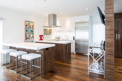 Inspiration for a mid-sized contemporary galley dark wood floor and brown floor eat-in kitchen remodel in Other with an undermount sink, flat-panel cabinets, white cabinets, quartz countertops, white backsplash, stainless steel appliances and two islands