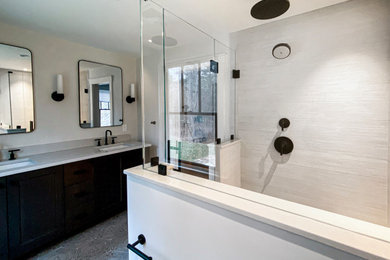 Example of a large trendy master beige tile and porcelain tile cement tile floor and gray floor corner shower design in Boston with shaker cabinets, a two-piece toilet, white walls, an undermount sink, quartzite countertops, a hinged shower door, white countertops and black cabinets