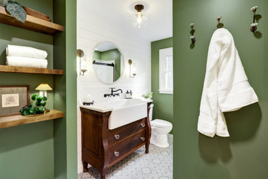 Mid-sized farmhouse master vinyl floor, multicolored floor, single-sink and shiplap wall bathroom photo in Other with brown cabinets, a two-piece toilet, green walls, a drop-in sink, quartz countertops, white countertops and a freestanding vanity
