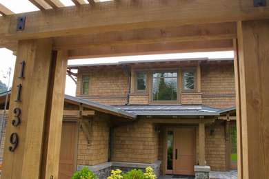 Example of a mid-sized arts and crafts brown two-story wood house exterior design in Vancouver with a hip roof and a metal roof