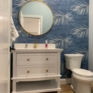 This is an example of a large transitional 3/4 bathroom in Other with recessed-panel cabinets, white cabinets, a one-piece toilet, blue walls, vinyl floors, an undermount sink, engineered quartz benchtops, brown floor, white benchtops, a single vanity, a built-in vanity and wallpaper.