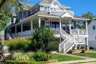 Large coastal gray three-story wood house exterior idea in Other with a mixed material roof