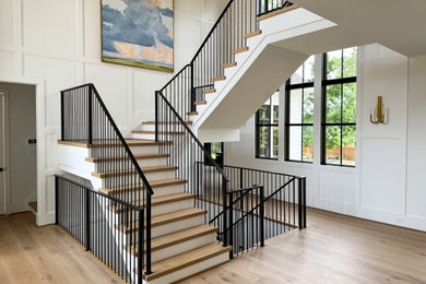 Large minimalist wooden u-shaped metal railing and wainscoting staircase photo in DC Metro with painted risers