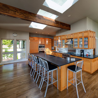 Photo of a contemporary l-shaped kitchen in Seattle with a submerged sink, glass-front cabinets, medium wood cabinets, multi-coloured splashback, mosaic tiled splashback, stainless steel appliances, medium hardwood flooring and an island.