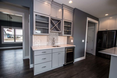 Example of a mid-sized transitional l-shaped dark wood floor and brown floor open concept kitchen design in Chicago with a farmhouse sink, shaker cabinets, gray cabinets, granite countertops, white backsplash, subway tile backsplash, stainless steel appliances and an island