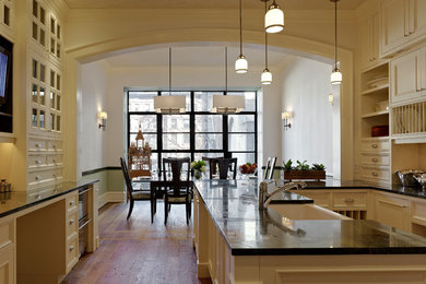 Inspiration for a large timeless u-shaped medium tone wood floor and brown floor eat-in kitchen remodel in New York with a farmhouse sink, recessed-panel cabinets, white cabinets, marble countertops, white backsplash, subway tile backsplash, stainless steel appliances and a peninsula