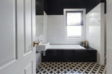 Small trendy 3/4 white tile and ceramic tile beige floor drop-in bathtub photo in Other with white walls and a wall-mount sink