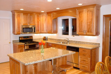 This is an example of a mid-sized traditional u-shaped eat-in kitchen in Salt Lake City with a double-bowl sink, raised-panel cabinets, light wood cabinets, granite benchtops, stainless steel appliances, light hardwood floors and with island.
