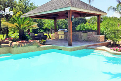 Photo of a tropical patio in Houston with an outdoor kitchen, natural stone pavers and a gazebo/cabana.