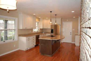 Example of a large mountain style single-wall kitchen design in Other with an undermount sink, raised-panel cabinets, distressed cabinets, granite countertops, brown backsplash, stainless steel appliances and an island