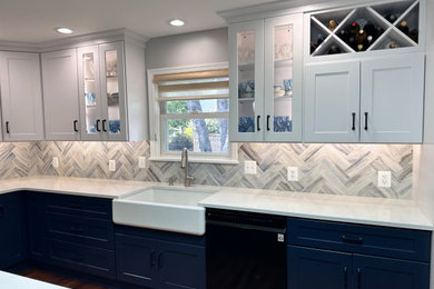 White upper cabinets with blue base cabinets with herringbone tile backsplash