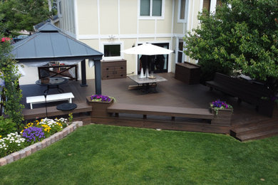 Huge backyard wood railing deck photo in Denver with a pergola