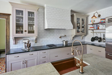 Example of a mid-sized ornate u-shaped medium tone wood floor and brown floor eat-in kitchen design in New York with a farmhouse sink, glass-front cabinets, gray cabinets, soapstone countertops, stainless steel appliances, an island and green countertops