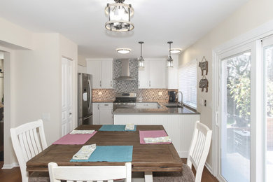 Mid-sized transitional u-shaped laminate floor and brown floor eat-in kitchen photo in Chicago with an undermount sink, recessed-panel cabinets, white cabinets, solid surface countertops, multicolored backsplash, glass tile backsplash, stainless steel appliances and gray countertops