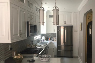 Mid-sized minimalist u-shaped terra-cotta tile and white floor eat-in kitchen photo in New York with a single-bowl sink, recessed-panel cabinets, white cabinets, quartzite countertops, gray backsplash, porcelain backsplash, stainless steel appliances, an island and white countertops