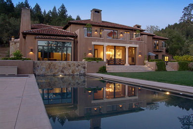Example of a large tuscan brown two-story stucco house exterior design in San Francisco with a hip roof and a tile roof