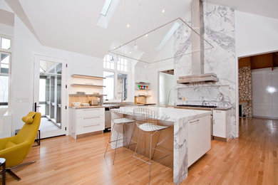 Eat-in kitchen - large contemporary single-wall medium tone wood floor eat-in kitchen idea in Cleveland with flat-panel cabinets, white cabinets, marble countertops, multicolored backsplash, stone slab backsplash, stainless steel appliances and an island