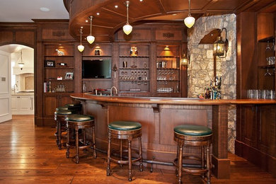 Elegant medium tone wood floor seated home bar photo in Nashville with shaker cabinets, dark wood cabinets, wood countertops and brown countertops