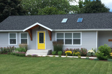 This is an example of a small country front porch design in Milwaukee with a roof extension.