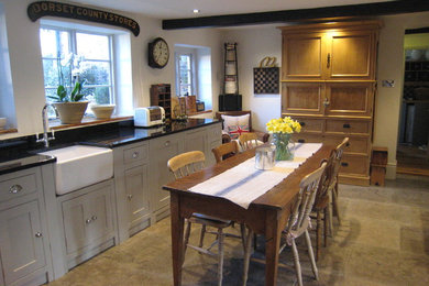 Medium sized rural l-shaped kitchen/diner with a belfast sink, shaker cabinets, grey cabinets, granite worktops, integrated appliances, limestone flooring and no island.