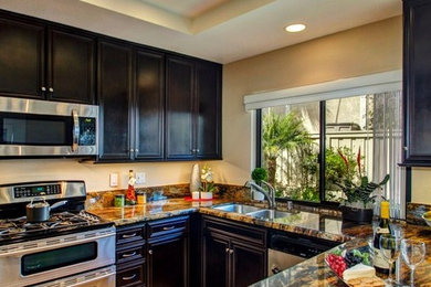 Kitchen - mid-sized transitional u-shaped kitchen idea in San Diego with dark wood cabinets, granite countertops, an undermount sink, stone slab backsplash and stainless steel appliances