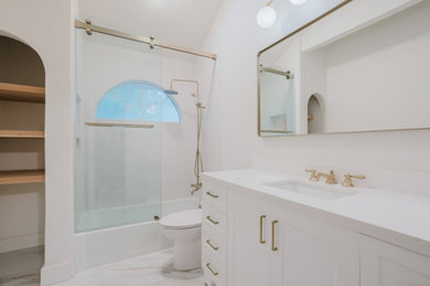 Bathroom - transitional white tile white floor and single-sink bathroom idea in Dallas with white cabinets, a one-piece toilet, white walls, white countertops and a niche
