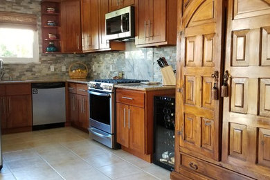 This is an example of a small country u-shaped eat-in kitchen in San Francisco with an undermount sink, shaker cabinets, medium wood cabinets, granite benchtops, grey splashback, stone tile splashback, stainless steel appliances, ceramic floors, beige floor and beige benchtop.
