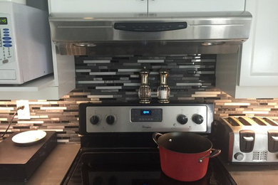 Inspiration for a mid-sized transitional kitchen remodel in Ottawa with raised-panel cabinets, white cabinets, matchstick tile backsplash, stainless steel appliances, quartzite countertops and multicolored backsplash
