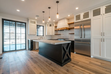 Example of a cottage l-shaped light wood floor eat-in kitchen design in Salt Lake City with a farmhouse sink, shaker cabinets, white cabinets, quartzite countertops, white backsplash, subway tile backsplash, stainless steel appliances and an island