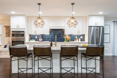 Inspiration for a large transitional galley medium tone wood floor and brown floor eat-in kitchen remodel in Other with shaker cabinets, white cabinets, quartz countertops, blue backsplash, porcelain backsplash, stainless steel appliances, an island, white countertops and an undermount sink