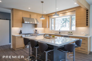 Example of a trendy u-shaped vinyl floor and brown floor eat-in kitchen design in Other with an undermount sink, flat-panel cabinets, light wood cabinets, solid surface countertops, white backsplash, ceramic backsplash, stainless steel appliances, an island and white countertops