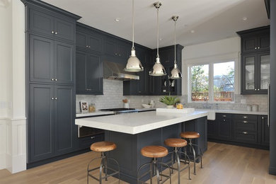Example of an arts and crafts u-shaped light wood floor kitchen design in San Francisco with a farmhouse sink, flat-panel cabinets, blue cabinets and stainless steel appliances