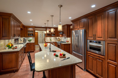 Eat-in kitchen - large traditional galley medium tone wood floor eat-in kitchen idea in Other with an undermount sink, raised-panel cabinets, dark wood cabinets, quartz countertops, beige backsplash, stone tile backsplash, stainless steel appliances and an island