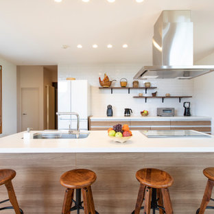 札幌の中くらいのコンテンポラリースタイルのおしゃれなキッチン (アンダーカウンターシンク、フラットパネル扉のキャビネット、淡色木目調キャビネット、白いキッチンパネル、ベージュの床、白いキッチンカウンター) の写真