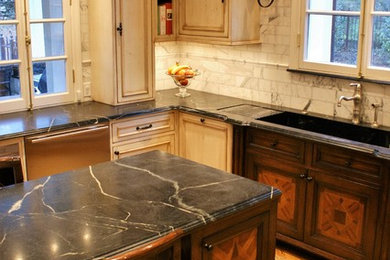 Enclosed kitchen - large traditional medium tone wood floor enclosed kitchen idea in Chicago with an integrated sink, raised-panel cabinets, distressed cabinets, soapstone countertops, white backsplash, stone tile backsplash, stainless steel appliances and an island