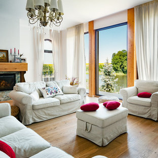 Foto de salón para visitas abierto, mediterráneo, de tamaño medio, con paredes blancas, marco de chimenea de piedra, suelo de madera en tonos medios, chimenea tradicional y suelo amarillo