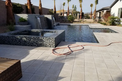 Large trendy backyard concrete paver and rectangular infinity pool fountain photo in Las Vegas