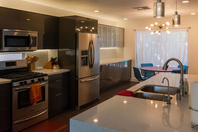 Mid-sized minimalist galley eat-in kitchen photo in Las Vegas with a double-bowl sink, glass-front cabinets, gray cabinets, marble countertops, white backsplash, glass tile backsplash, stainless steel appliances, an island and white countertops