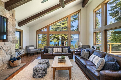 Example of a large mountain style dark wood floor, vaulted ceiling and wood wall living room design in Sacramento with a standard fireplace and a stone fireplace