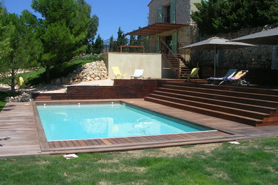 Idée de décoration pour une piscine latérale méditerranéenne rectangle avec une terrasse en bois.