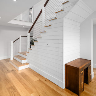 Modelo de escalera en L y machihembrado, de estilo de casa de campo, con escalones de madera, barandilla de cable y machihembrado