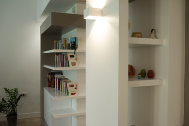 Foto på ett stort funkis allrum med öppen planlösning, med vita väggar, marmorgolv, beiget golv, ett bibliotek och en fristående TV