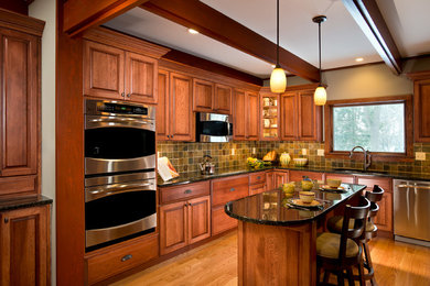 Eat-in kitchen - large craftsman l-shaped light wood floor and beige floor eat-in kitchen idea in Boston with an undermount sink, raised-panel cabinets, medium tone wood cabinets, granite countertops, multicolored backsplash, stone tile backsplash, stainless steel appliances and an island