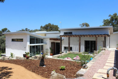 This is an example of a mid-sized contemporary split-level adobe white exterior in Other.
